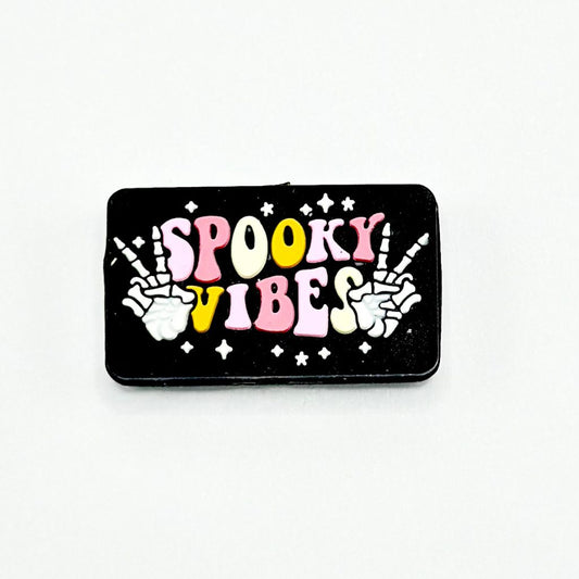 カラフルな文字「Spooky Vibes」が書かれた黒いビーズと、手の形の頭蓋骨のシリコン製フォーカルビーズ